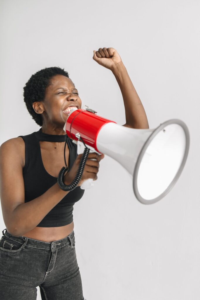 Black woman passionately shouting into a megaphone, expressing activism and emotion.